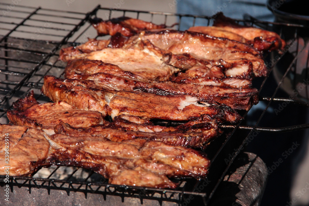 A large steak of grilled meat with smoke. Cooking in the open air.