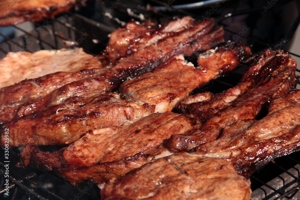 A large steak of grilled meat with smoke. Cooking in the open air.