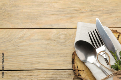 Table setting. wooden stand and cutlery in a white napkin, fork, spoon and knife on a natural wooden table. top view
