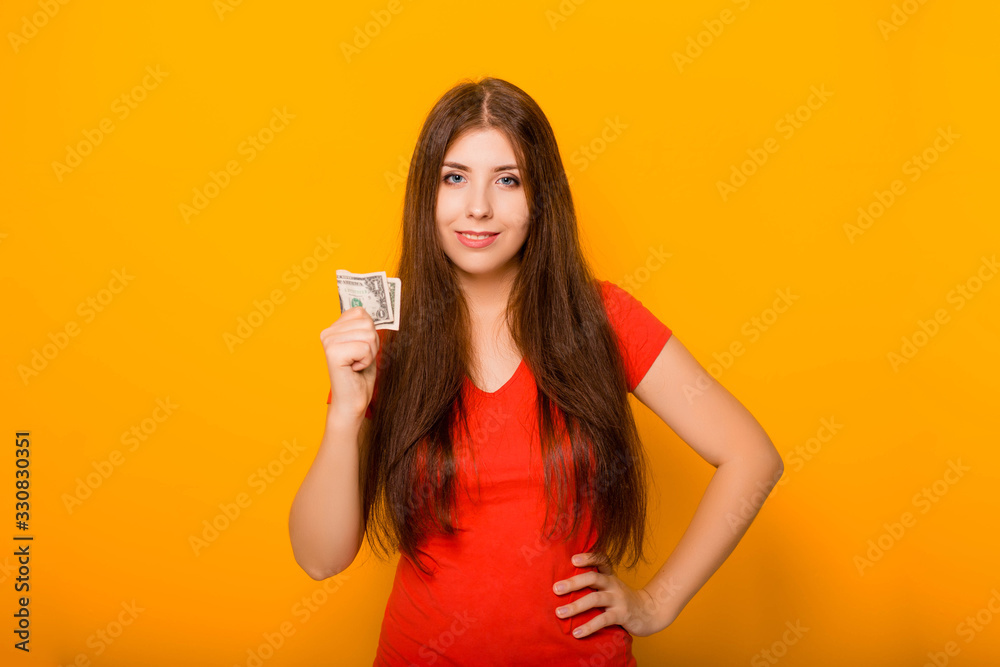 Attractive, young woman holds money notes in her hands, concept of savings and cashback. Studio photo on a yellow background. Attractive, young woman holds money notes in her hands, concept of savings and cashback. Studio photo on a yellow background.