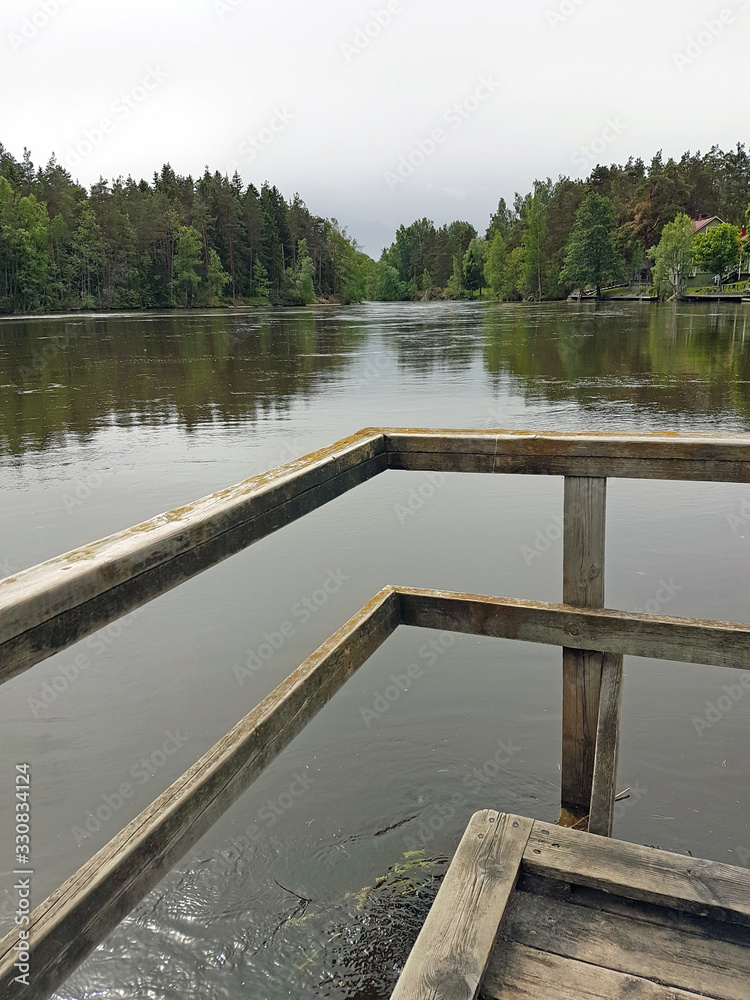 wooden handrails of a small pier on a forest lake