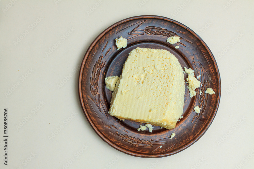 Fat cheese on a brown plate on a white background