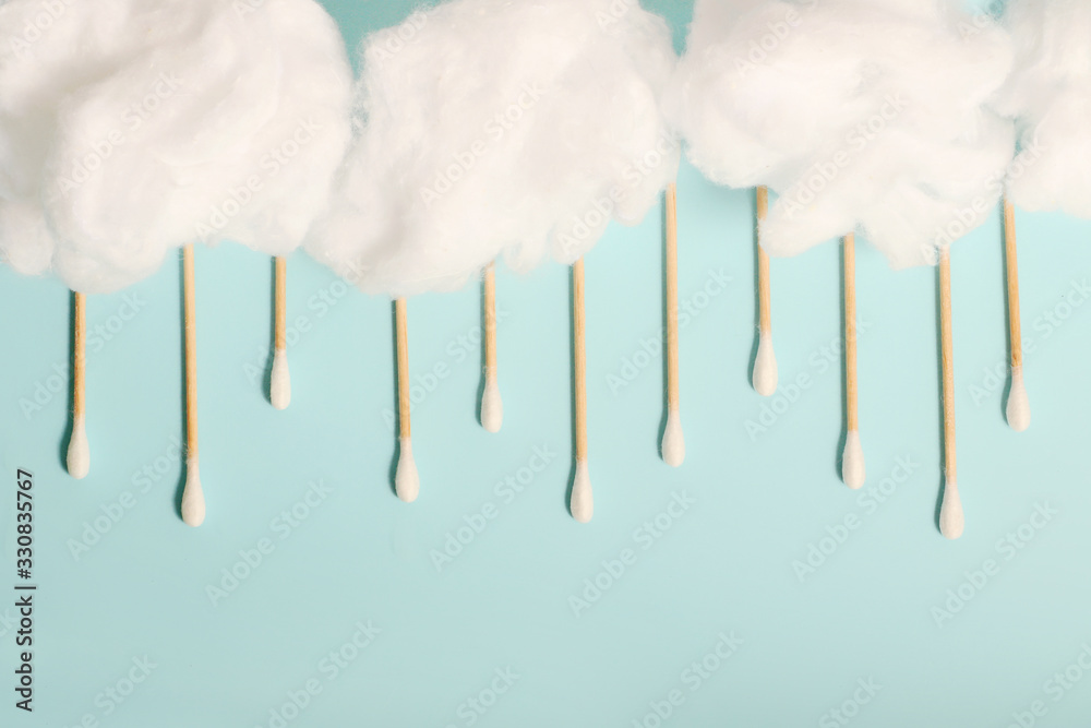 Rain from wooden ear sticks.Natural Cotton Buds For Eye Cleaning.Blue backdrop.Cotton clouds.