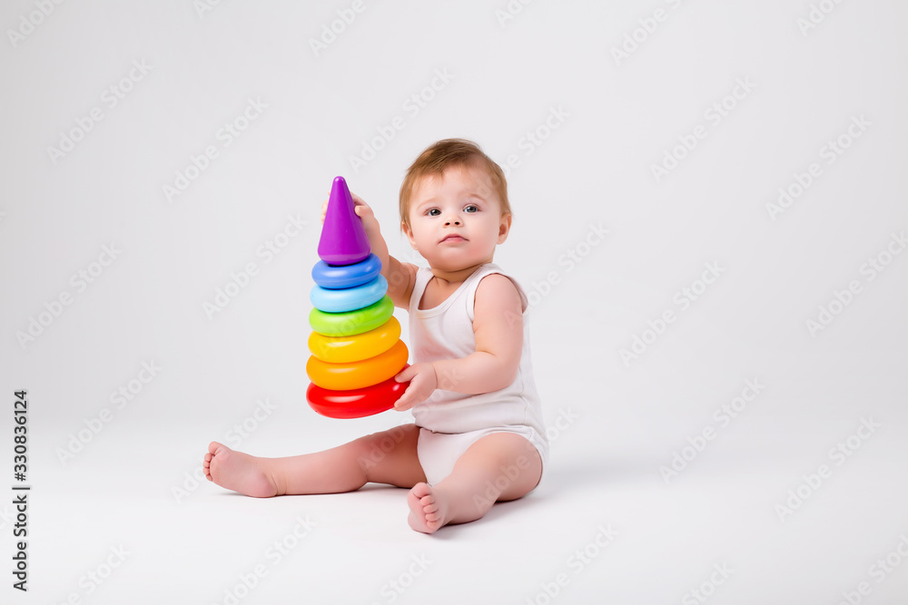 healthy baby girl sitting playing with an educational toy on a white background isolate healthy baby girl sitting playing with an educational toy on a white background isolate