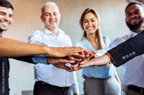 Cheerful Business People Holding Hands Standing In Circle In Office © Prostock-studio