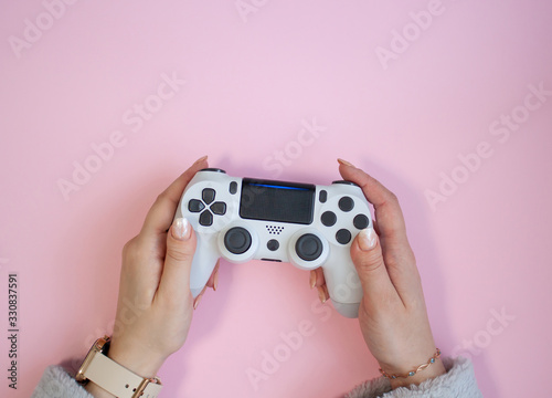Hands holding a white gamepad on pink background