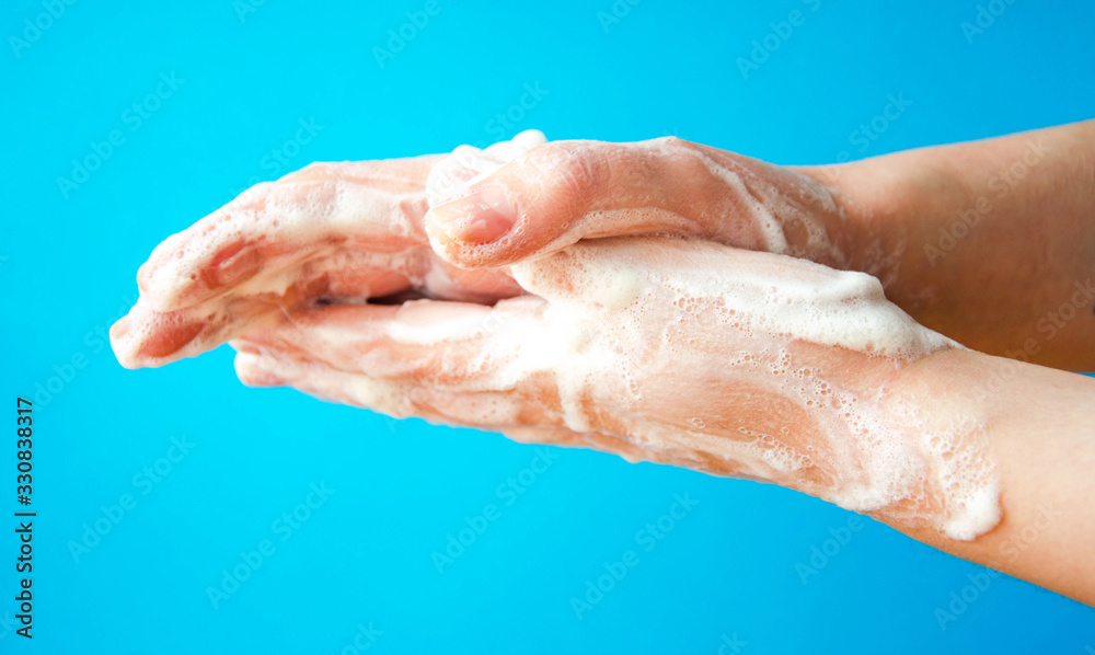 Women's hands are holding soap. Soap foam on the hands. Yellow soap in the hands. Woman washes soap with hands side view on a blue background. Virus protection. COVID-19 Women's hands are holding soap. Soap foam on the hands. Yellow soap in the hands. Woman washes soap with hands side view on a blue background. Virus protection. COVID-19