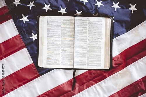 Closeup shot of the Bible open in pages put on the American flag - perfect for praying concept
