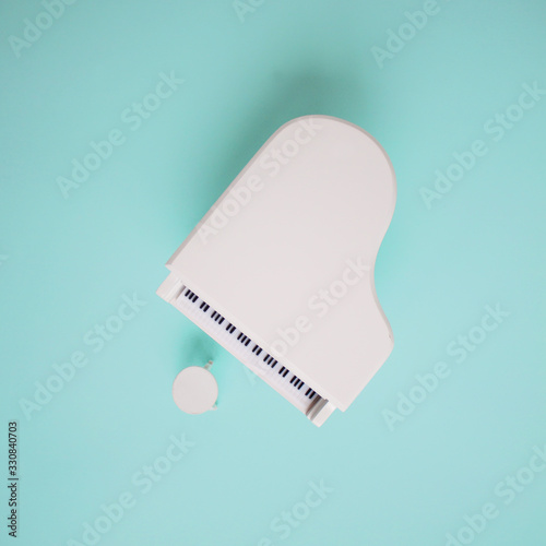 Toy white grand piano on turquoise background
