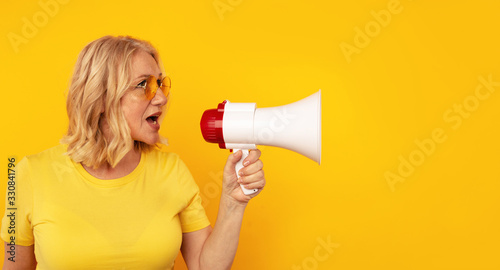 Woman with megaphone isolated in the yellow studio