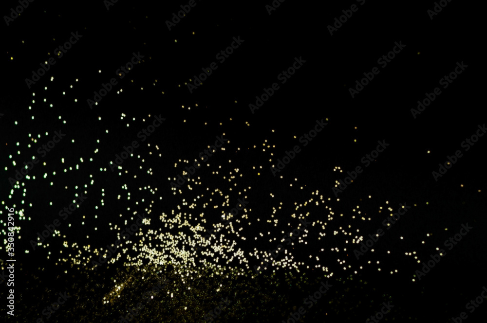 Black background with golden sparkles. Blurred effect. Concept for festive background.Close-up