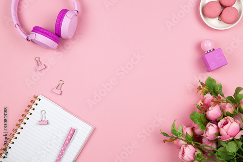 Modern female working space, top view. Women's or girls things, wireless headphones, roses, perfume, stationery on pink backround, copy space, flat lay. Work from home concept. For blog. Horizontal © AllUneed