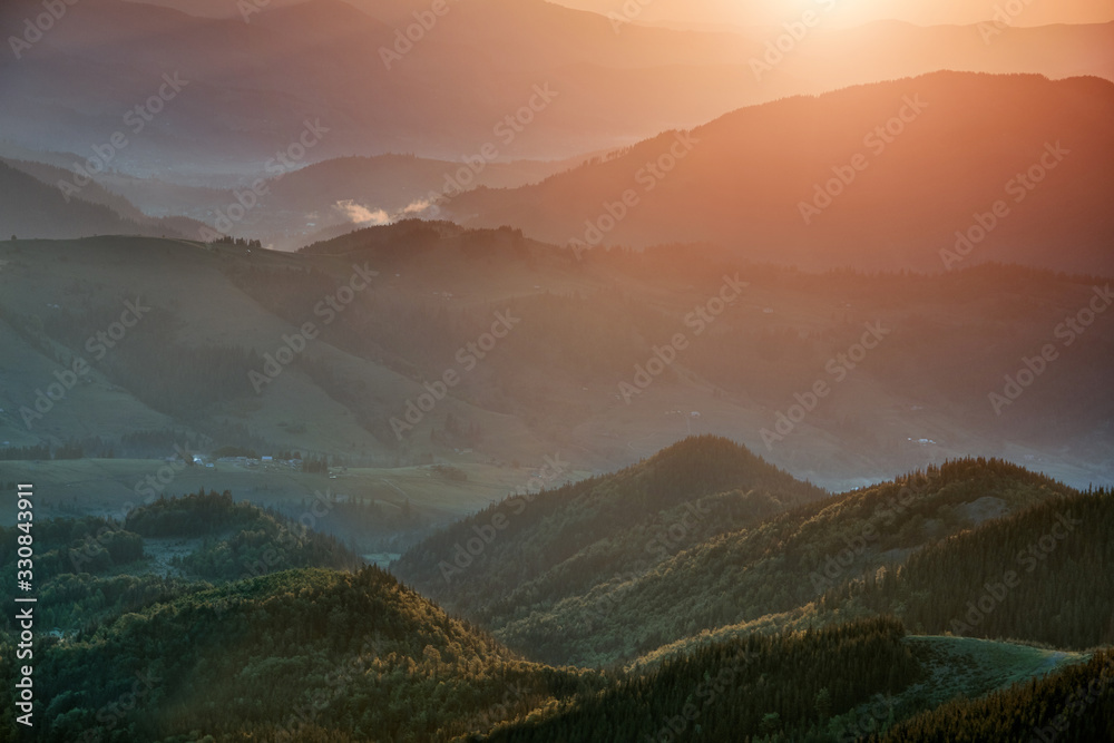 View of the top on fantastic sunlight of beautiful scenery mountains range at sunrise. Summer landscape. Concept of the awakening wildlife. Nature background.