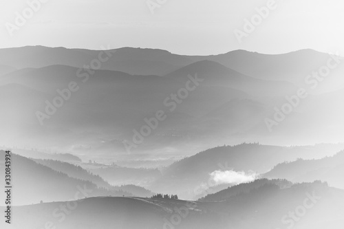 View of the top on fantastic sunlight of beautiful scenery mountains range at sunrise. Layers of mountain and haze in the hills at distance. Black and white landscape. High key photography background.