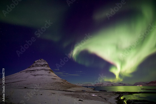 Strong Northern light pass over a beautiful mountain covered with snow with clear sky 