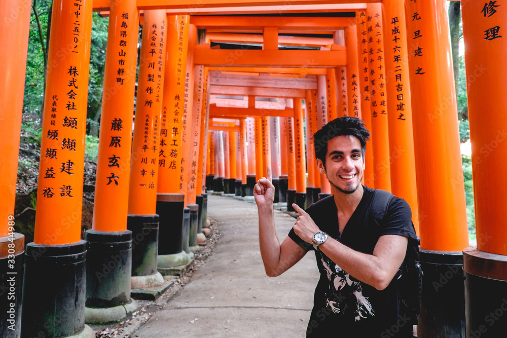 Fototapeta premium Happy traveler and torii gates path at Fushimi Inari taisha shrine, Kyoto