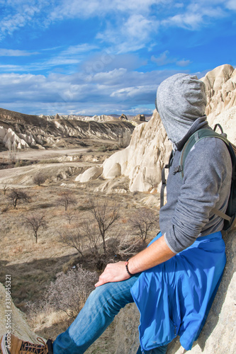 Tourist looks to distant white valley in Kapadokya. with rocky geologcal formations in the background. Exploration of interesting geologcal sites and red valley.