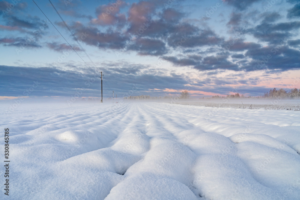 Obraz premium Winter sunrise over snow covered field with round shape snow piles .