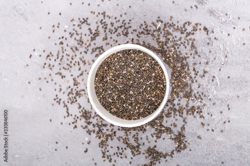 Chia seeds in bowl, on a grey background, top view.