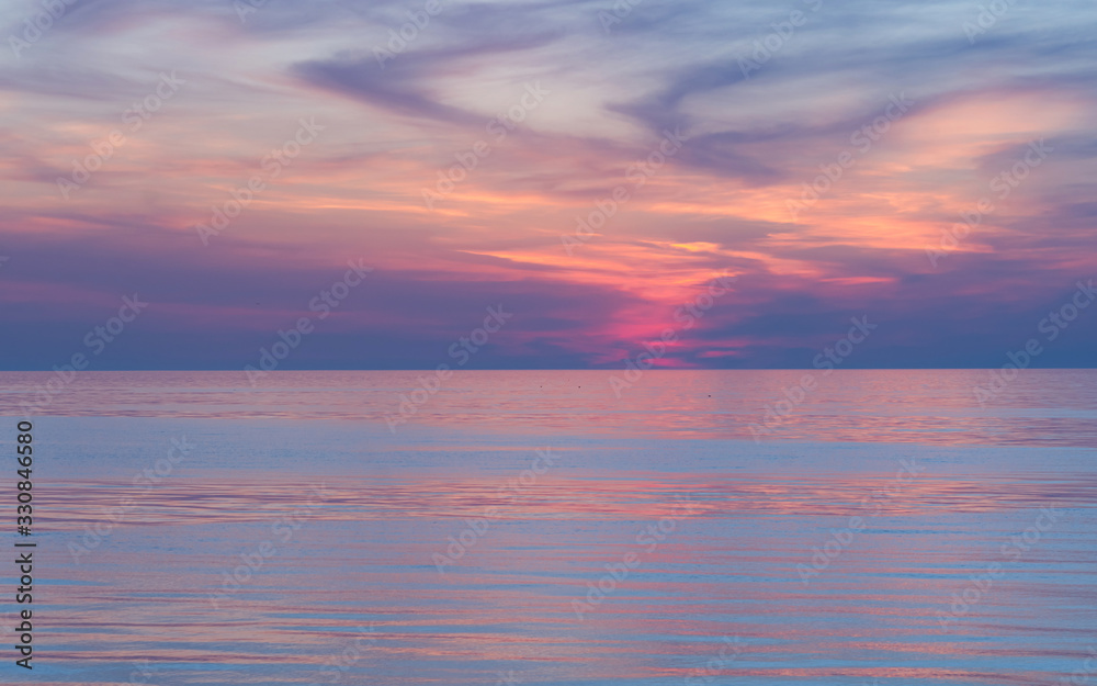 Pink sunset on the sea. Twilight Dusk. Beautiful clouds over the calm sea.