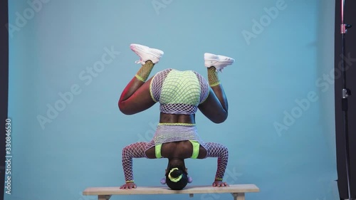 African dancehall queen doing headstand and twerking on the bench in slowmotion photo