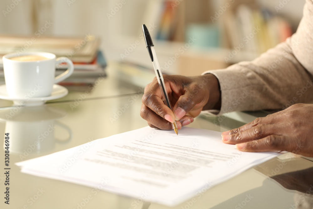 © PheelingsMedia - Black man hands singing contract on a desk