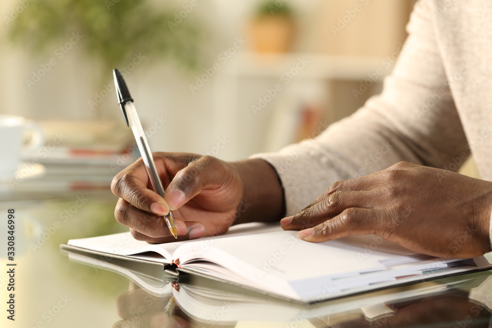 Black man hands writing reminder on agenda Black man hands writing reminder on agenda