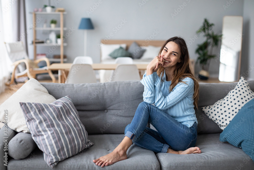 Obraz premium Relaxed smiling woman sitting on sofa at home.