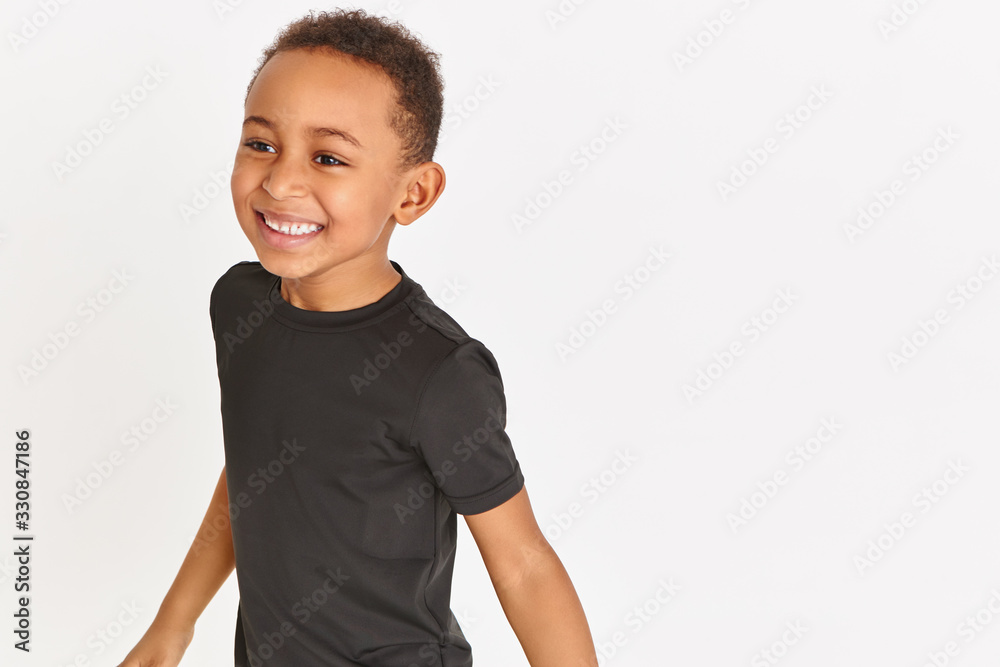 Close up image of handsome emotional dark skinned little boy with short Afro hair wearing black t-shirt having fun, laughing out loud, opening mouth widely, showing his white straight teeth Close up image of handsome emotional dark skinned little boy with short Afro hair wearing black t-shirt having fun, laughing out loud, opening mouth widely, showing his white straight teeth
