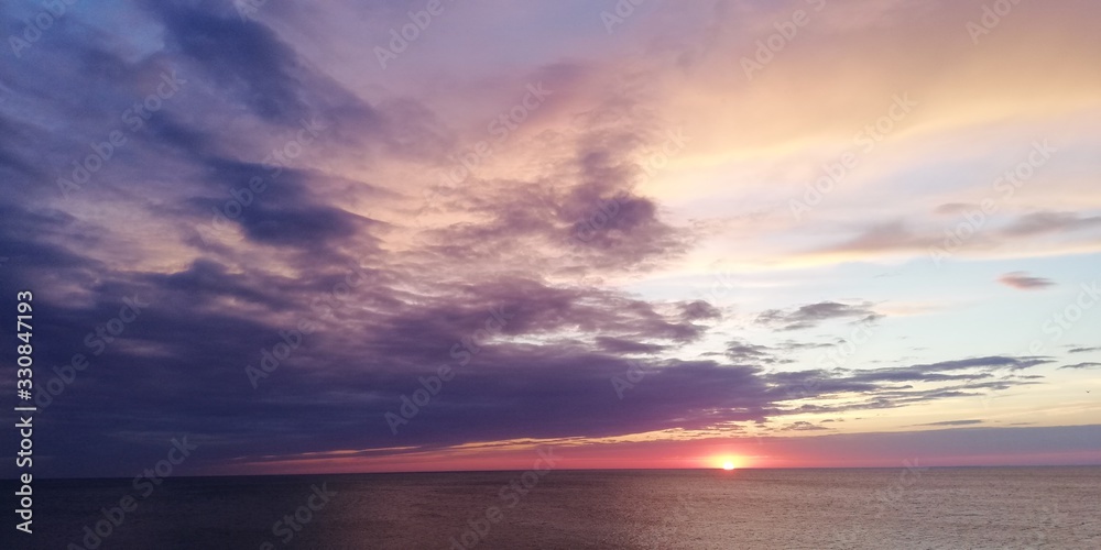 Dramatic disturbing landscape of stunning sea sunset in purple and orange tones. Dark clouds in the sky of amazing beauty. The mood of flight, infinity, tragedy