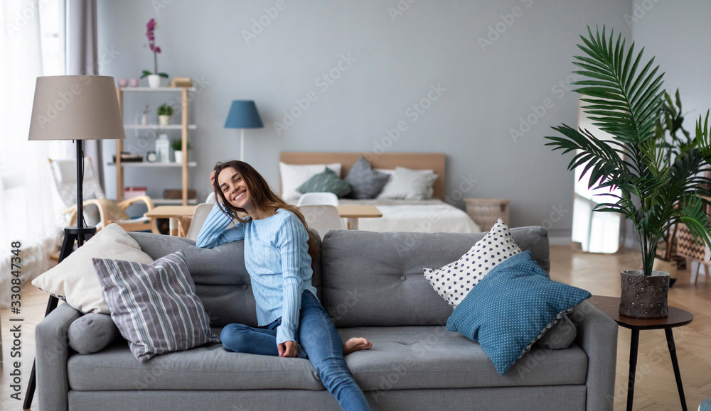 Tranquil smiling millennial woman leaning on sofa. Tranquil smiling millennial woman leaning on sofa.