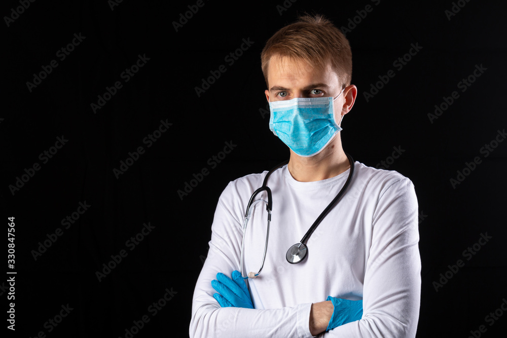 Young doctor in medical mask on a black background Young doctor in medical mask on a black background