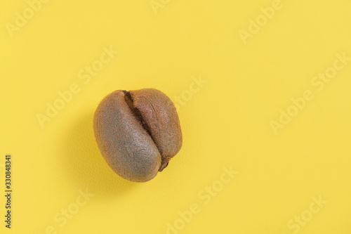 Ugly misshapen fruit kiwi on yellow background. Top view with copy space