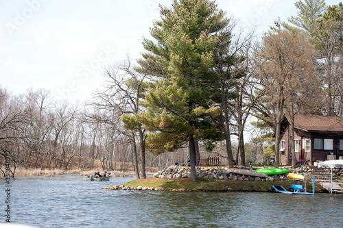Fishing boat on lake channel and cabin with field stone by the shore. Nisswa Minnesota MN USA