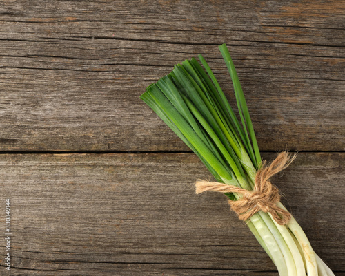 fresh green onion leaves tied with a rope in a bunch on a gray wooden background