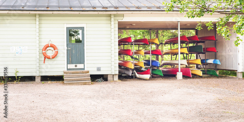 colorful kayaks stored on racks at boat station near white building in spring