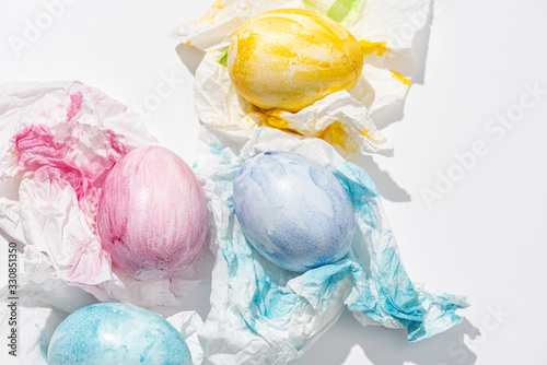  Freshly painted Easter eggs are dried on paper napkins. White background. Top view.