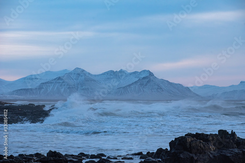 Wild coast in Icealnd with snow covered mountains in the background