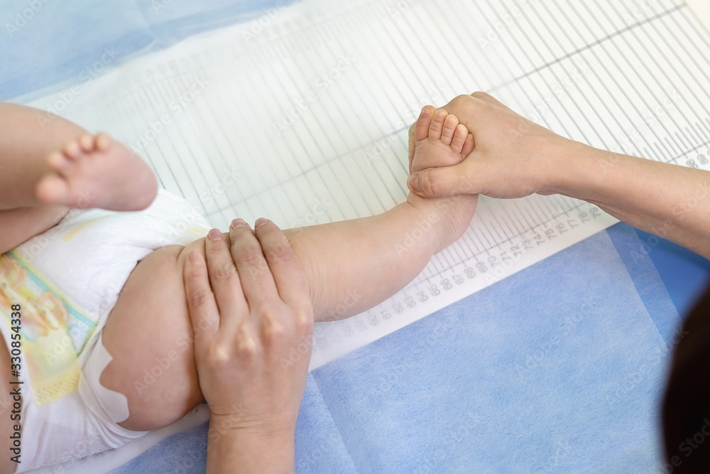 Pediatrician specialist taking measurement of infant child height during screening examination. Doctor or nurse holding child leg to take measure of person length. Children healthcare and prevention - obrazy, fototapety, plakaty 