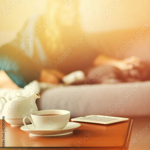 Cozy home interior with teapot, cup of tea and eBook
