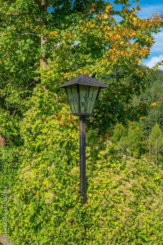 old rusty lantern in green trees with blue cloudy sky old rusty lantern in green trees with blue cloudy sky