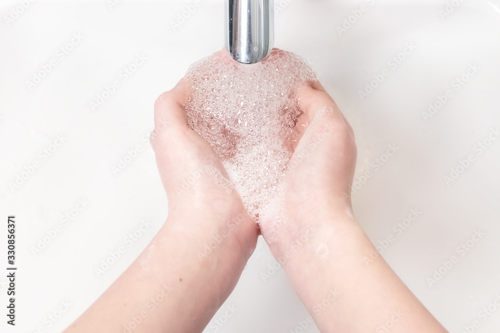 Fototapeta premium Washing hands with soap under the faucet with water
