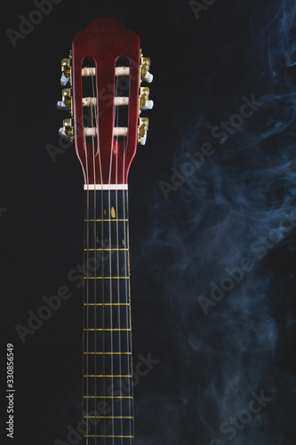 Acoustic guitar in smoke on the black background. musical instrument. strings on the guitar neck