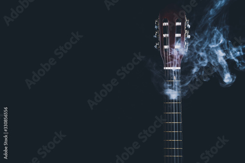 Acoustic guitar in smoke on the black background. musical instrument. strings on the guitar neck