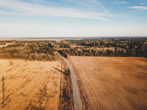 Road and agricultural fields aerial view. meadow landscape with roadway