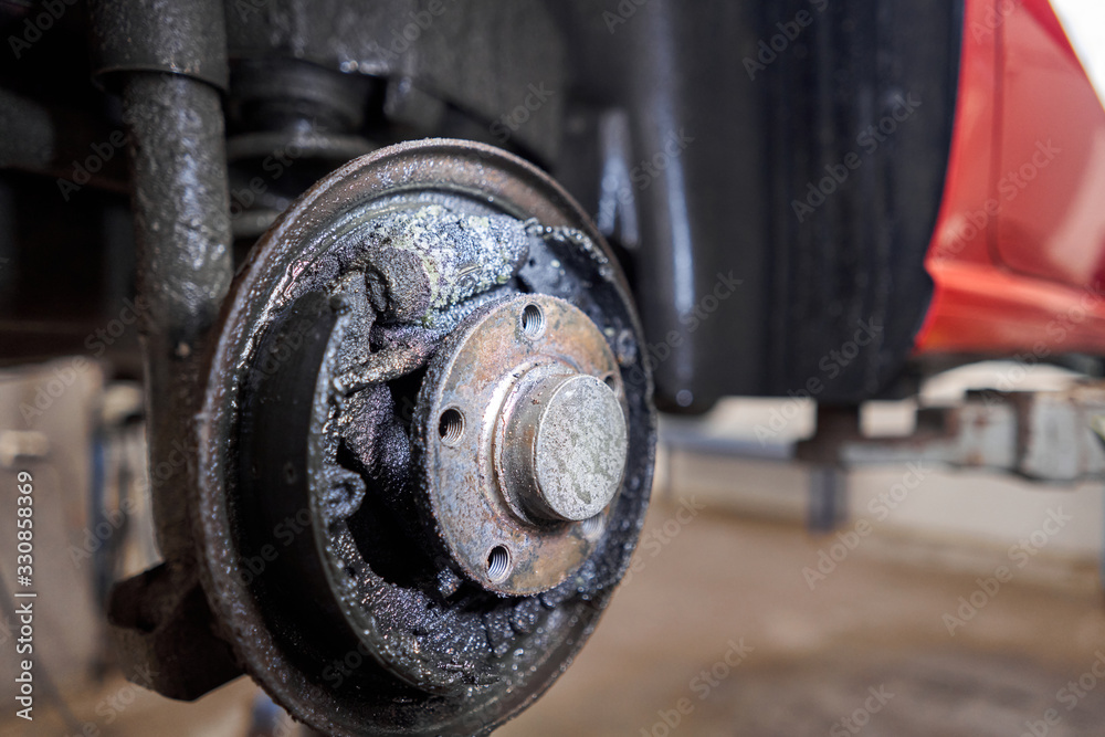 Rusty drum brakes, rear on red car. Change the old to new brake disc on car in a garage. Auto mechanic repairing Rusty drum brakes, rear on red car. Change the old to new brake disc on car in a garage. Auto mechanic repairing