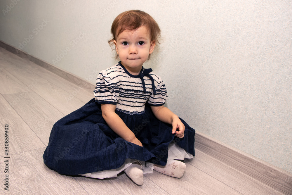 a little girl in a dress sitting on the floor a little girl in a dress sitting on the floor