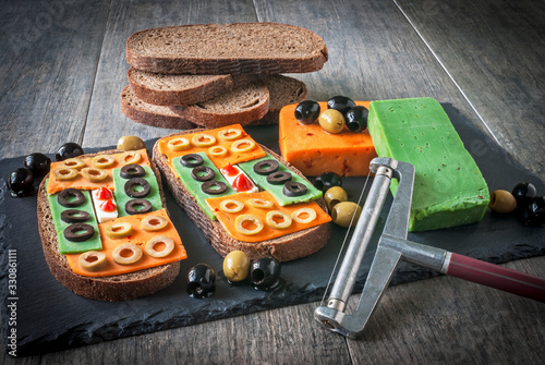 Still life of sandwiches, bread, cheese and olives.