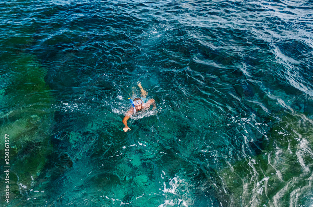 Obraz premium a man dives with glasses and tube and bathes in the sea with turquoise blue color