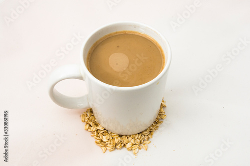 Cup of coffee on a white background with oatmeal. Latte in a white cup. © Katerina